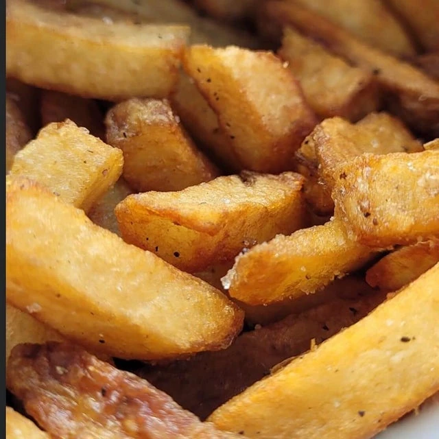 Close-up of golden-brown french fries from a mobile kitchen, seasoned with salt and pepper.