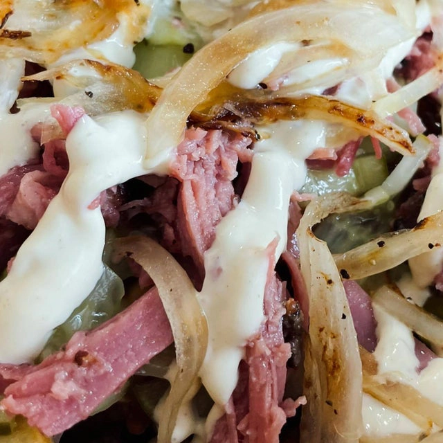 Close-up of a reuben sandwich from a mobile kitchen with layers of sliced corned beef, swiss cheese, sauerkraut, and creamy dressing on rye bread.